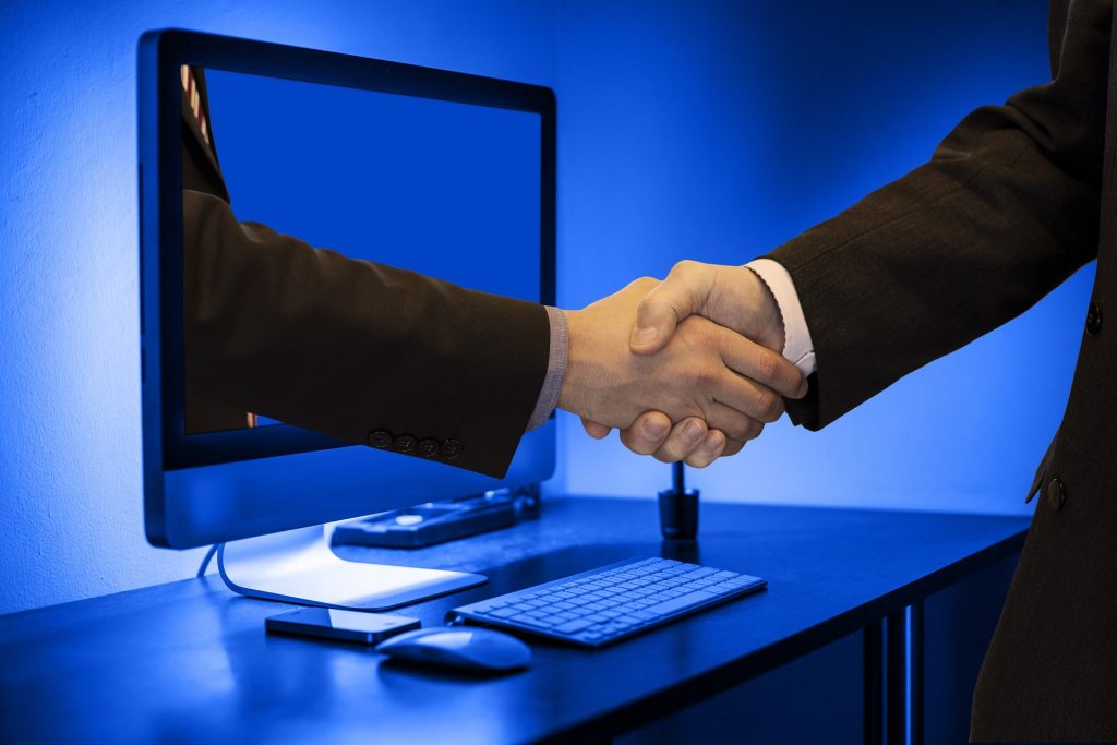photo de deux personne se serrant la main depuis un pc pour illustrer la visibilité en ligne